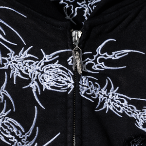 Close up of a black zip hoodie with white embroidered designs and a silver angel zipper puller
